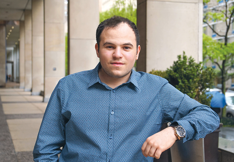 white man with dark hair in blue oxford shirt sitting outside