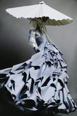modle in blue floorlength dress with ruffles and large hat obscuring face.