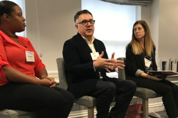 Stephan Kanlian sitting between two women at a conference