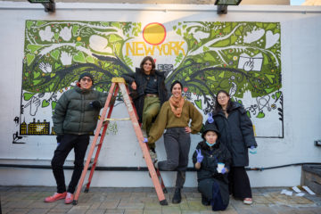 students on ladder painting a mural