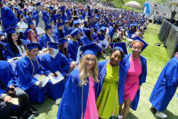 crowd of seated students in caps and gowns at commencement