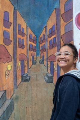 student standing in front of their mural as part of Chalk FIT