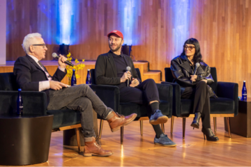 three people sitting on a stage in chairs talking