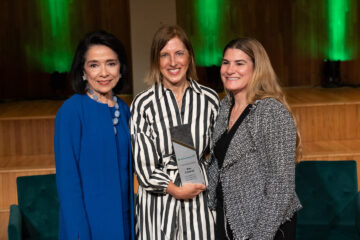 Three women in business suits posing with an award