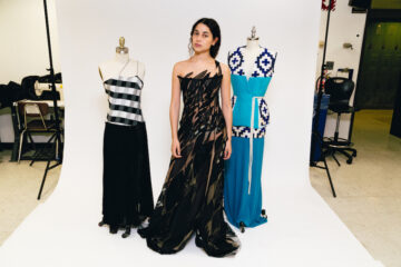 model stands with two dress forms presenting the three winning garments of the RealReal competition